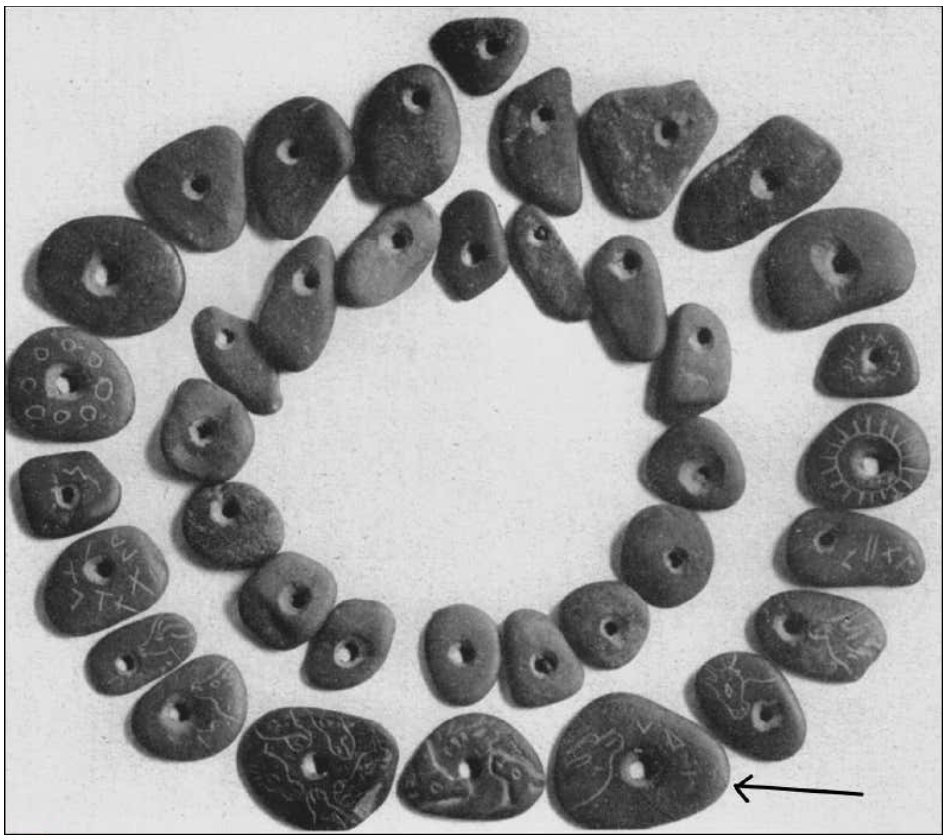 Figure 4. Collier formé de galets perforés. L’inscription concernée figure sur le galet en basa droite (signalé par une flèche). (Photo Antonin Morlet)